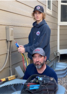 image of 2 HVAC service techs working on an air conditioner representing How Often Should I Service My Air Conditioner?